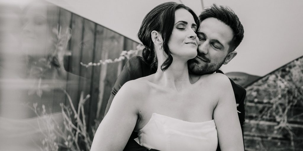 Bräutigam umarmt Braut von hinten