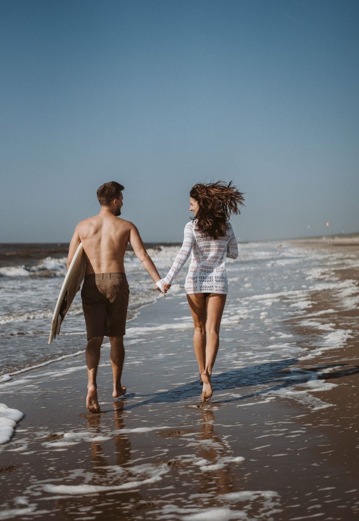 Paar am Strand mit Surfbrett