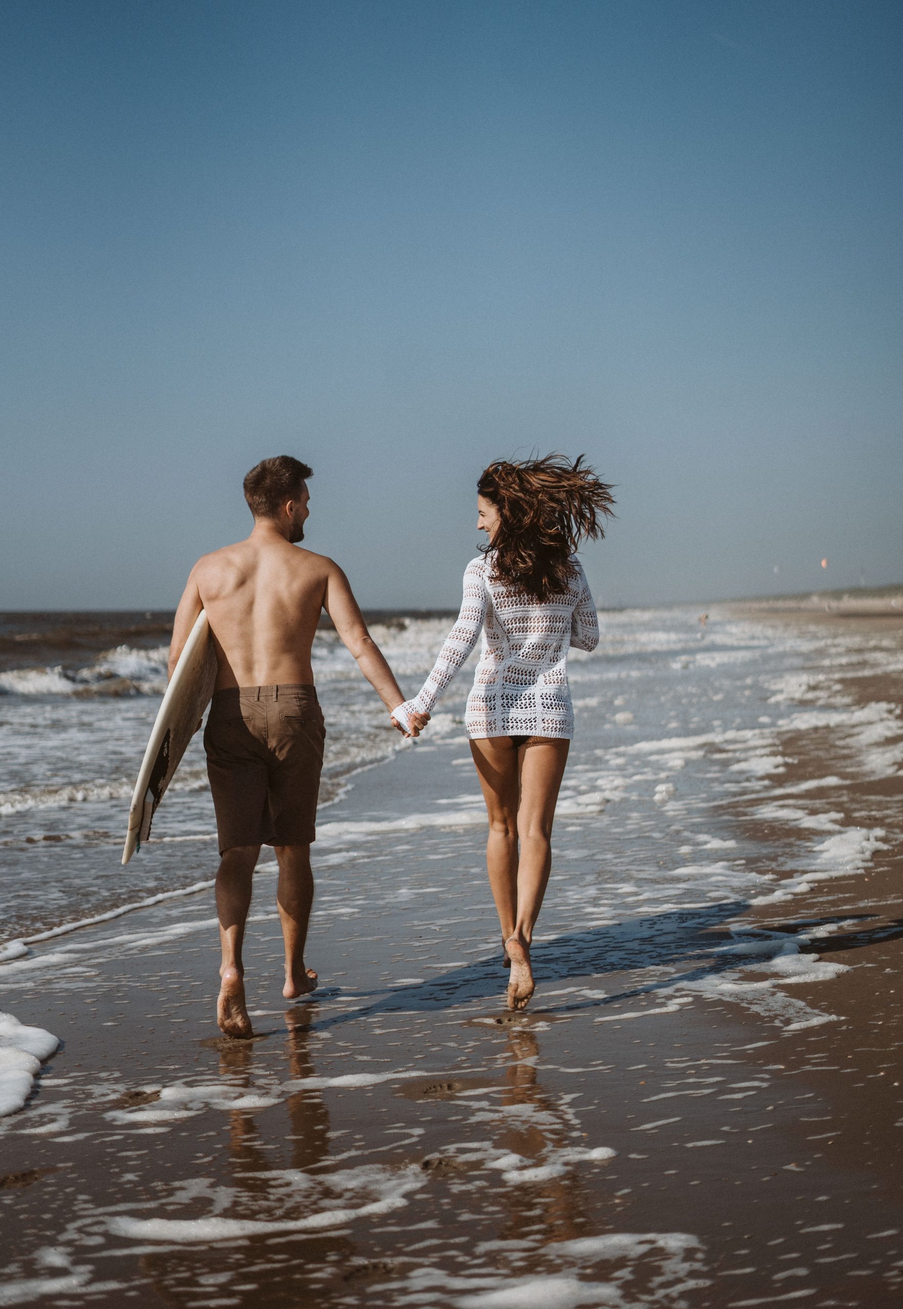 Paar am Strand mit Surfbrett