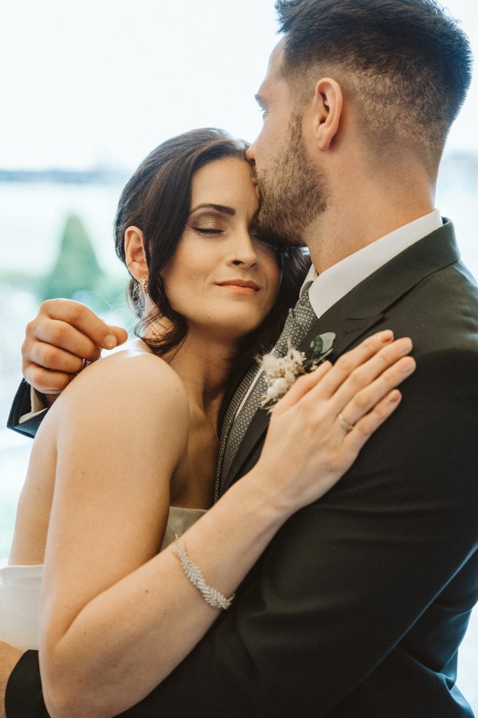 Bräutigam küsst Braut auf die Stirn Umarmung