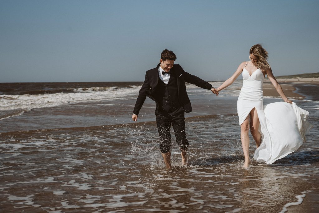 Brautpaar laufen durchs Wasser am Meer