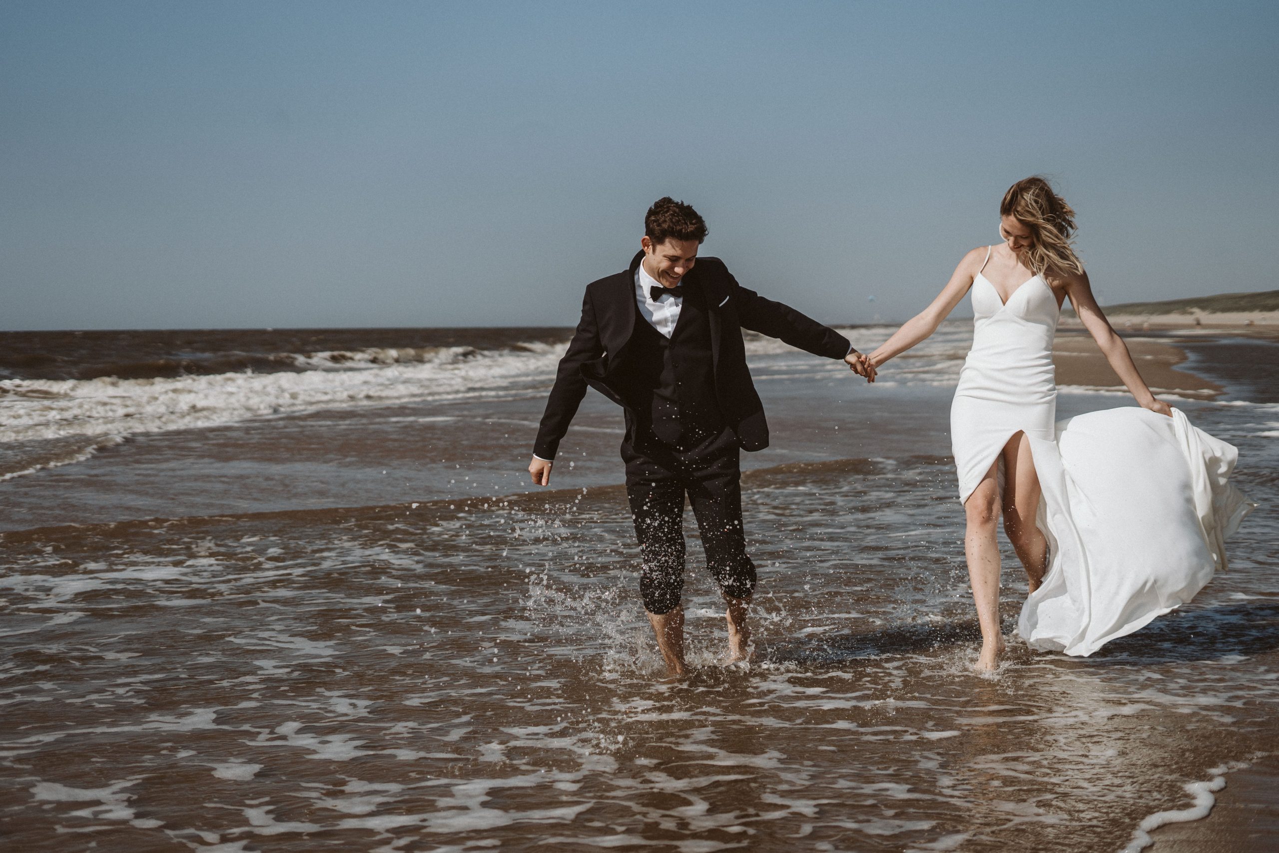 Brautpaar laufen durchs Wasser am Meer