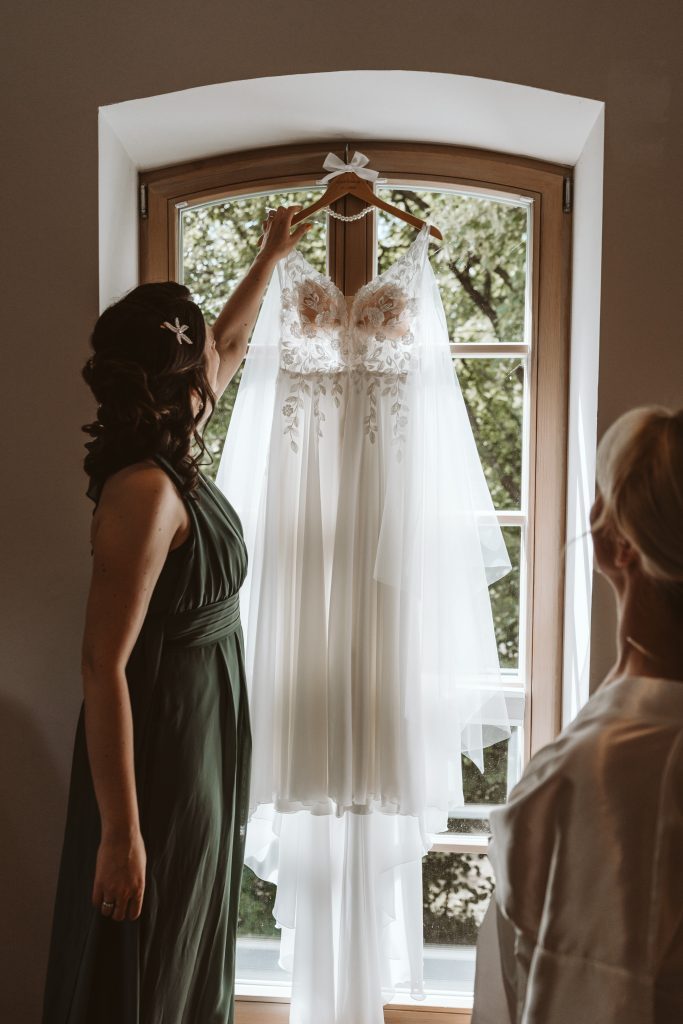 Freundin reicht Braut das Brautkleid
